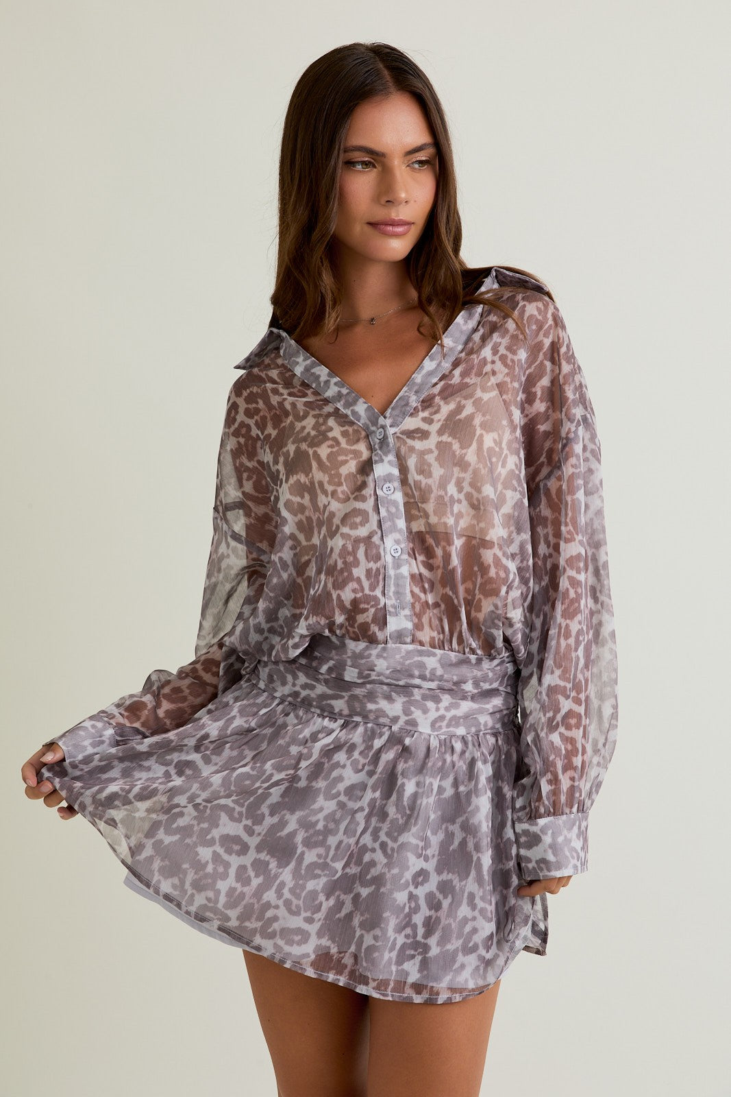Model wearing Midnight Safari Shirt Dress, a sheer leopard print button-front mini dress with low waist fit.