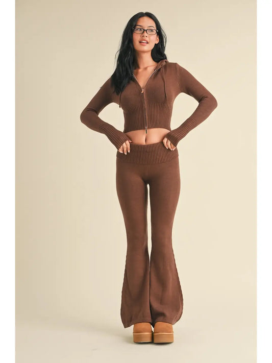 Woman wearing a brown outfit with flared pants on a beige background