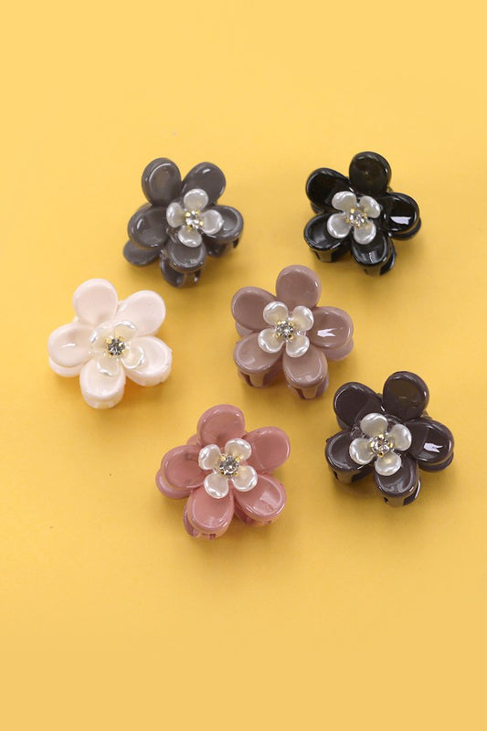 Six pastel daisy flower mini claw clips arranged on a yellow background