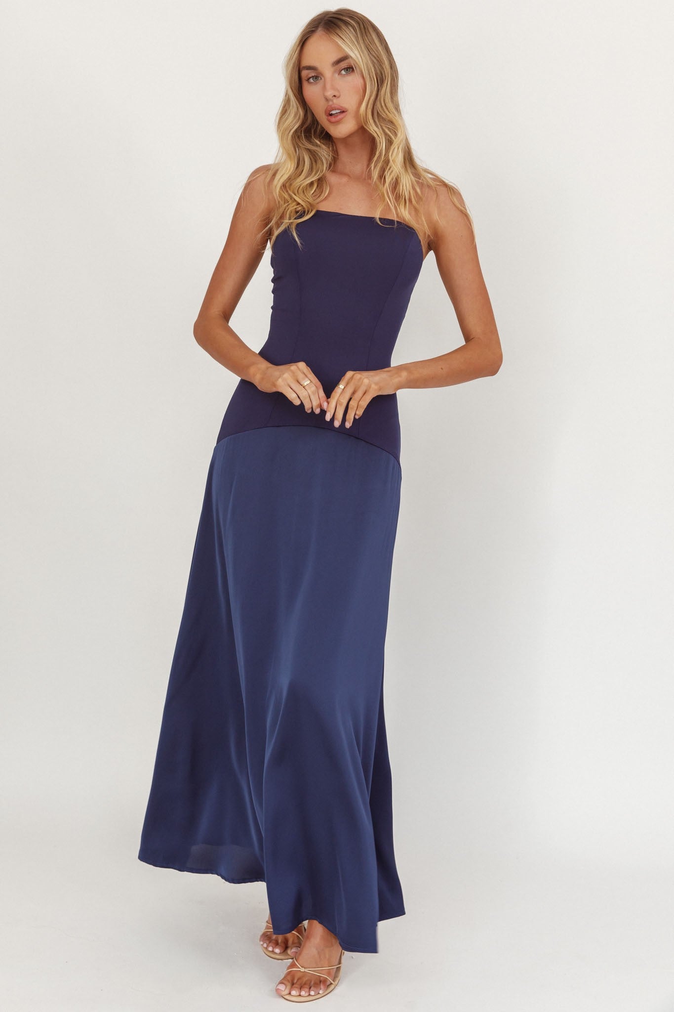 Model wearing Midnight Grace Strapless Dress in navy with fitted bodice and flowing maxi skirt