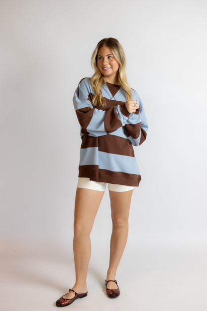 Woman wearing a brown and blue striped sweater on a white background