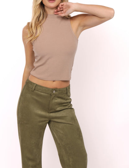 Model wearing black sleeveless mock neck knit top tucked into olive green pants