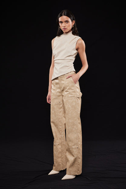 Model wearing a beige sleeveless top and pants on a black background
