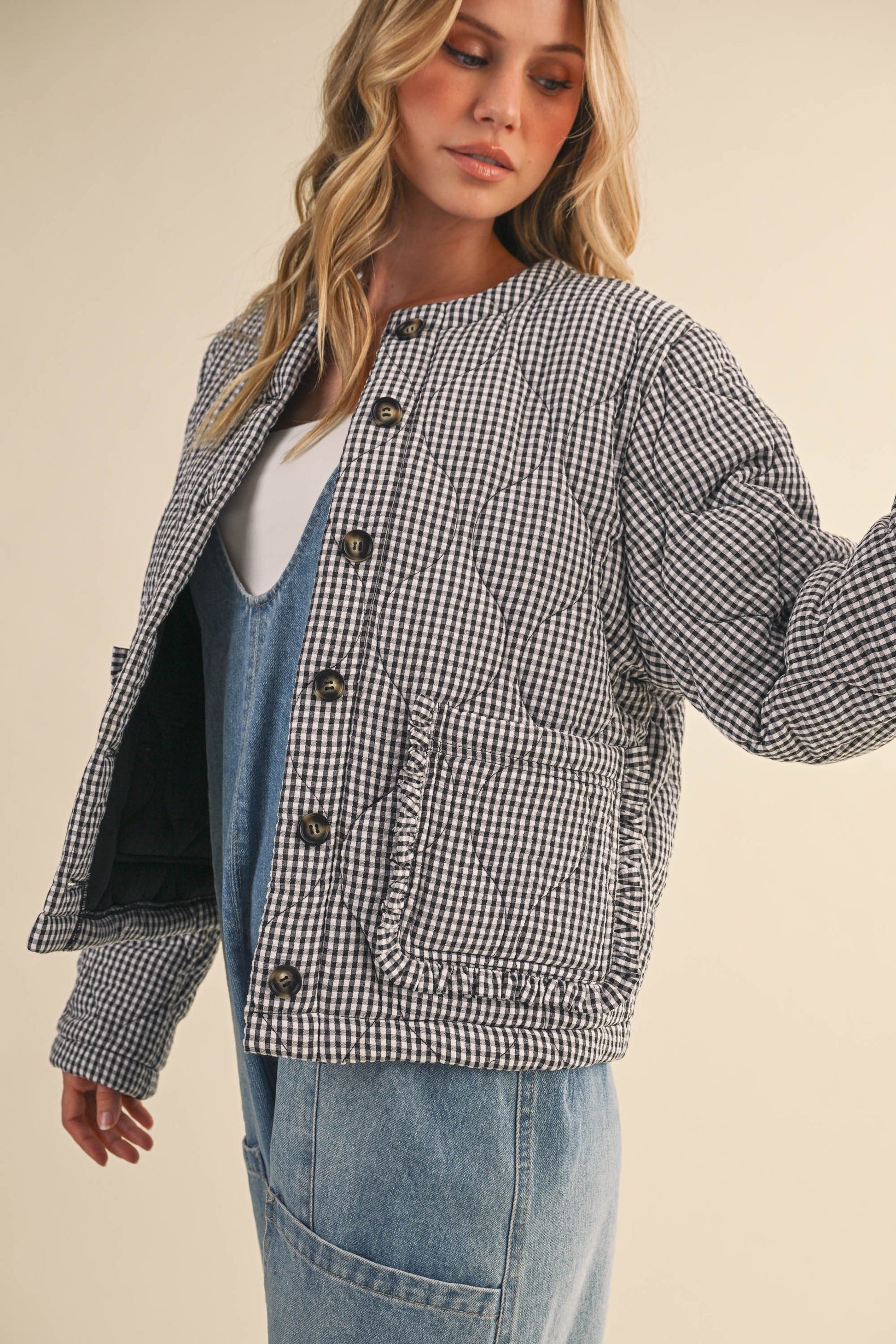 Woman wearing a checkered jacket over a denim outfit on a beige background