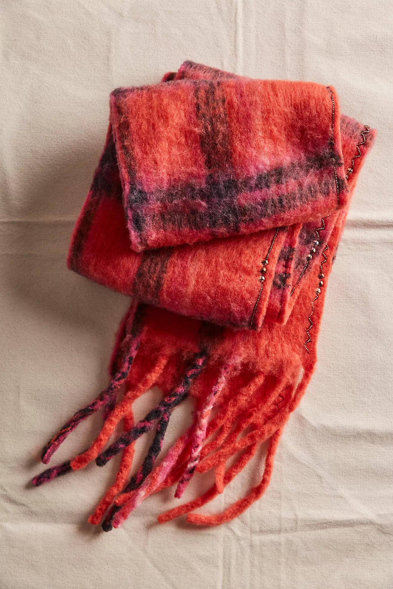 Red plaid scarf with fringes on a beige background