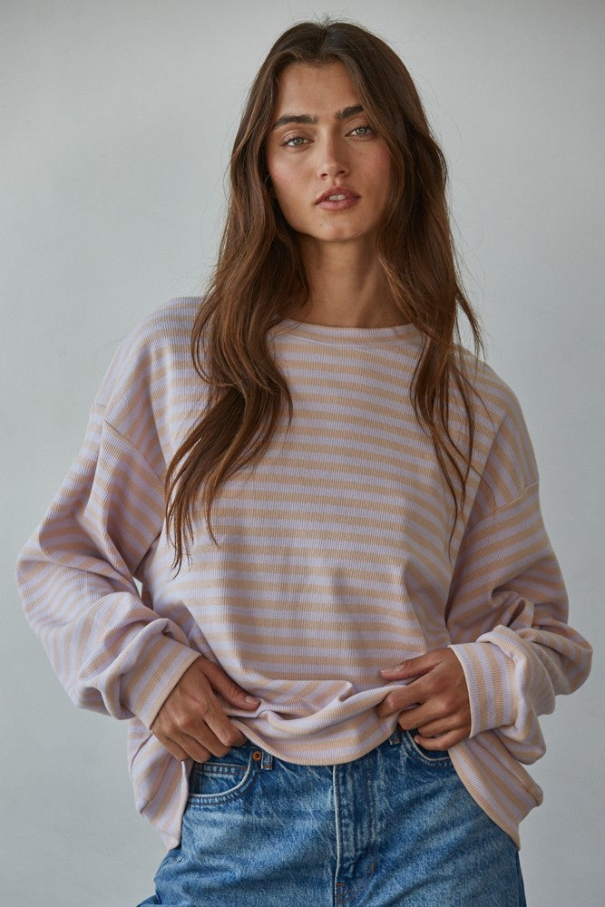 Woman wearing pastel lavender and cream striped long sleeve top with ribbed crew neck and relaxed fit