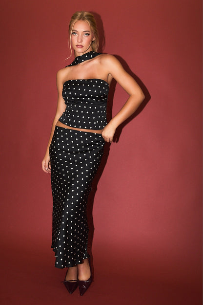 Model wearing black satin polka dot bias-cut maxi skirt with matching halter top
