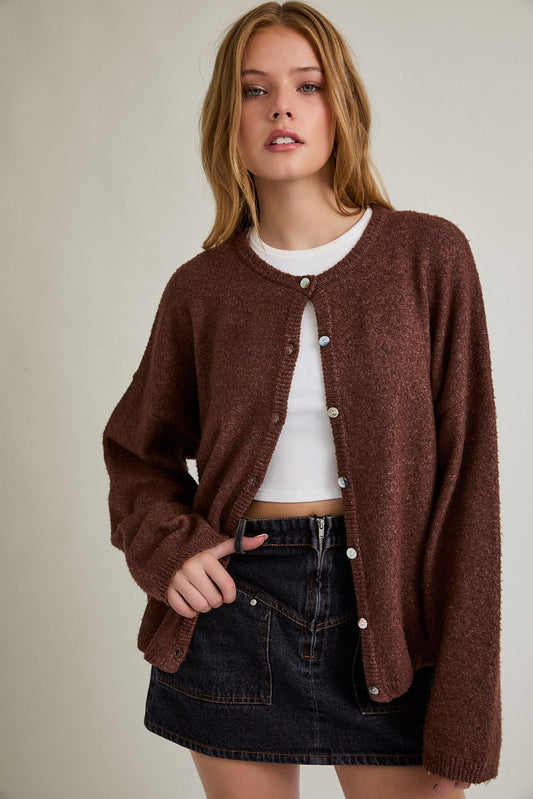 Brown crew neck button cardigan with long sleeves and relaxed fit layered over a white tank top.