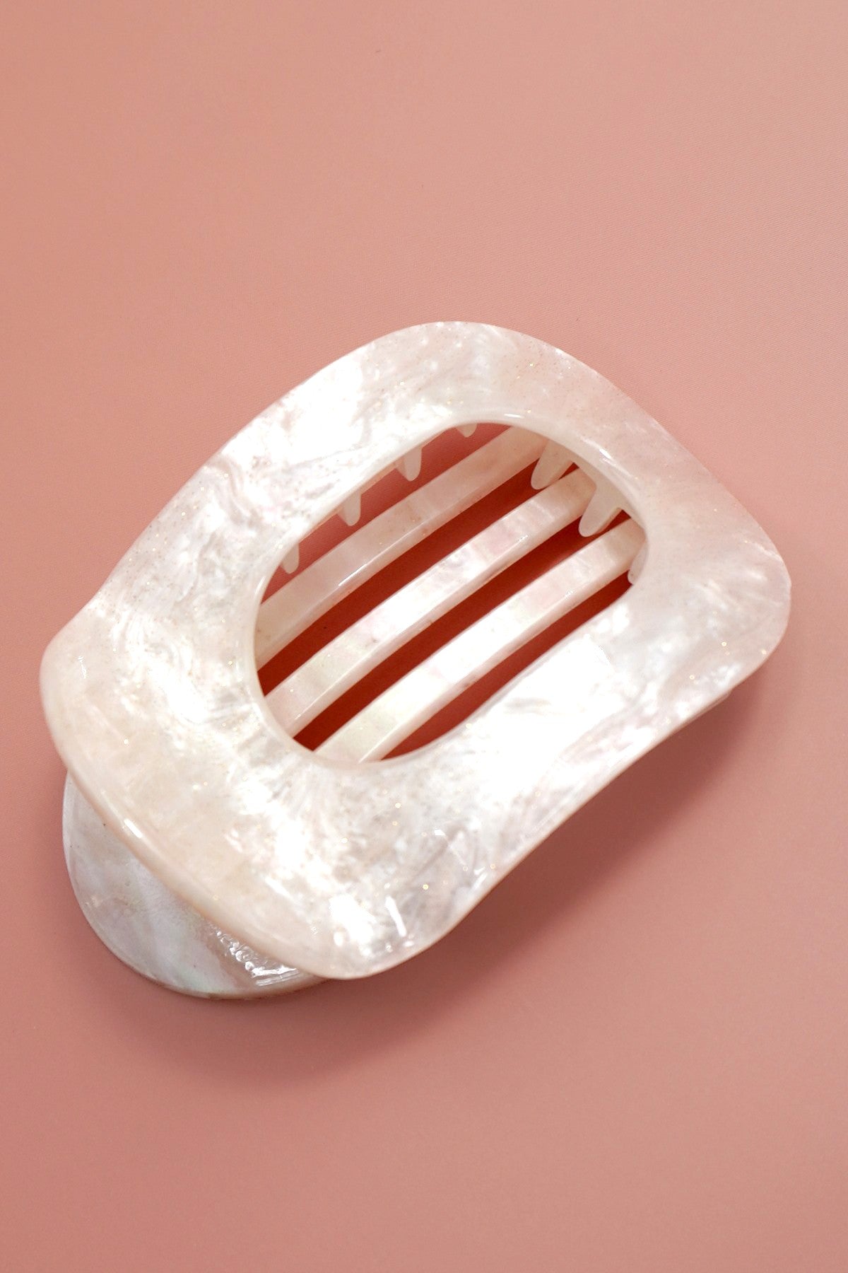 Rectangular claw clip with a textured surface on a pink background