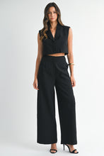 Load image into Gallery viewer, Model wearing a sleeveless black cropped vest and matching wide-leg pants with heels against a white background