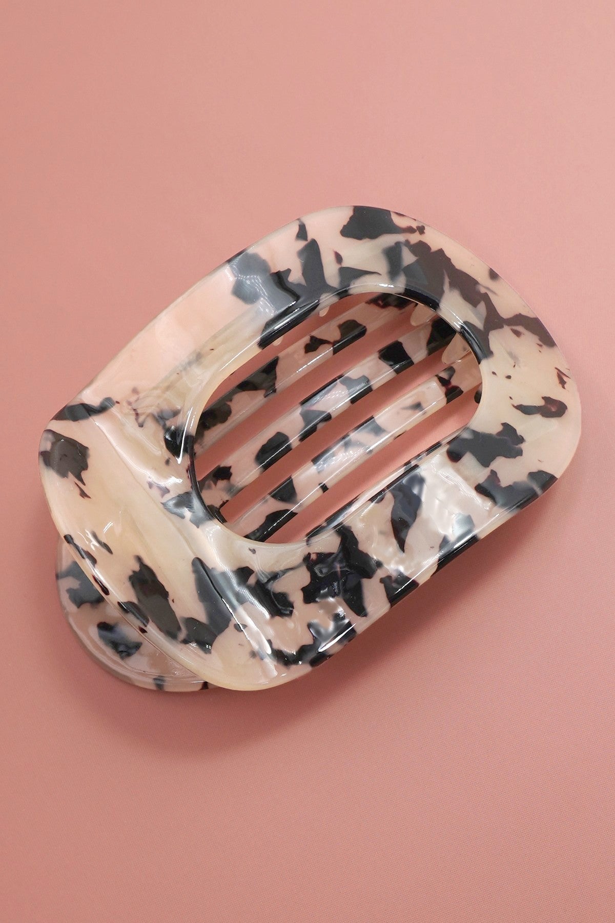 Floral-patterned hair clip on a pink background