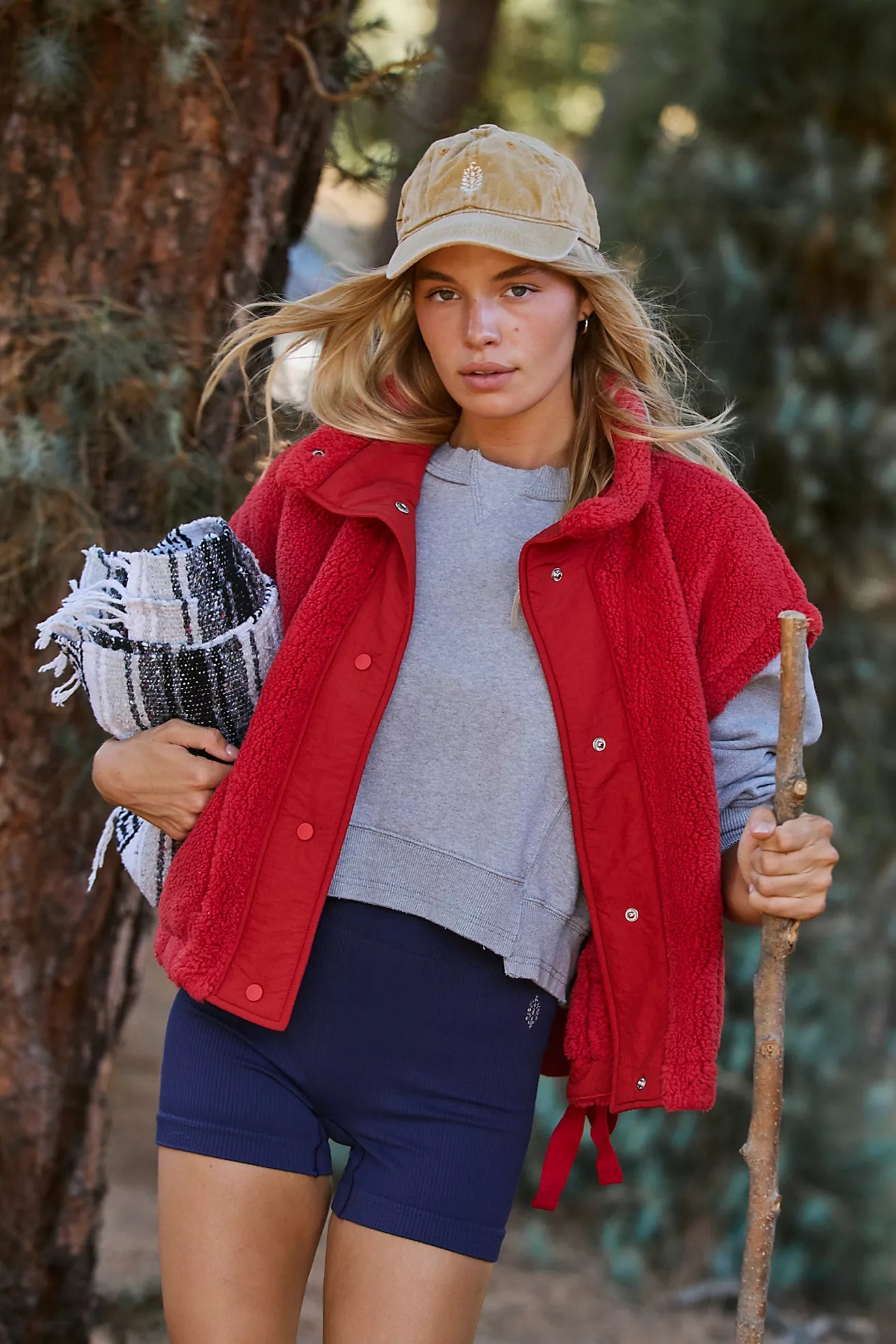 woman wearing cranberry fleece vest with grey sweatshirt and navy shorts in outdoor setting