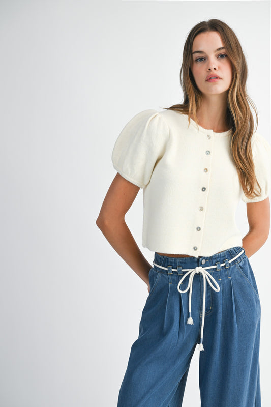 Woman wearing a white blouse with puff sleeves and blue jeans on a white background