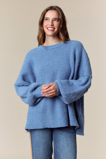 Woman wearing a soft blue oversized knit sweater with round neckline and relaxed silhouette