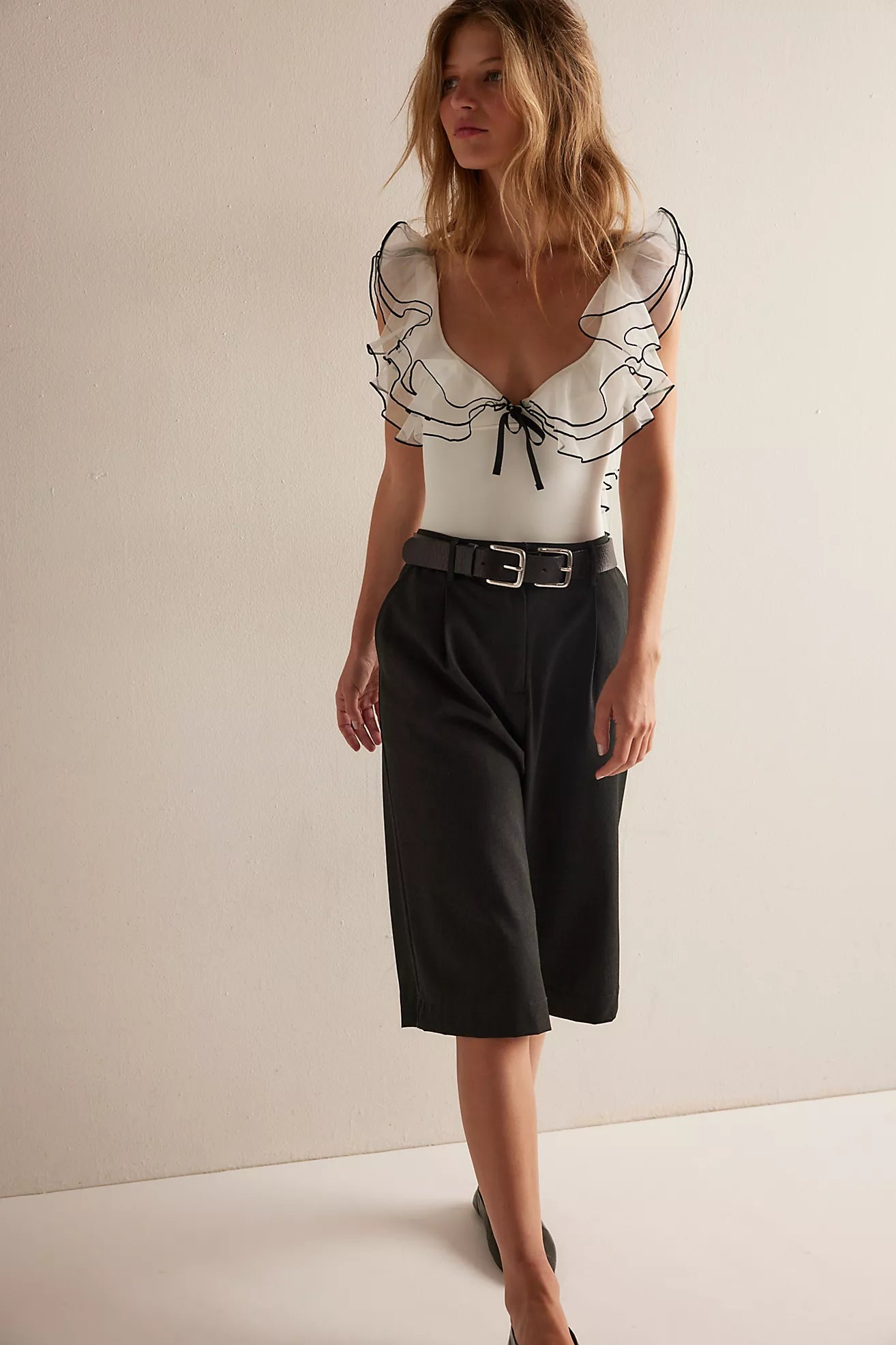 Woman wearing the Sugar Rush Bodysuit, a sheer ruffle bodysuit with tie-front closure and thong bottom.
