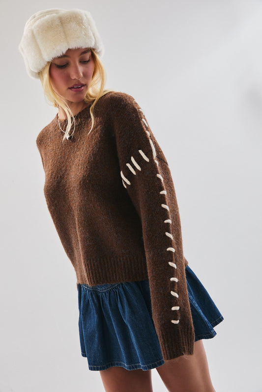 Model wearing Chestnut Stitch Knit sweater in brown with contrast whipstitch sleeve details