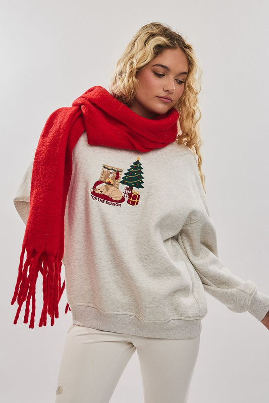 Woman wearing a beige sweater with Christmas design and a red scarf on a white background