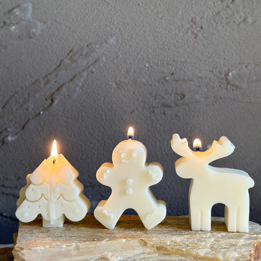 Three candle-shaped figures on a wooden surface with a gray textured background